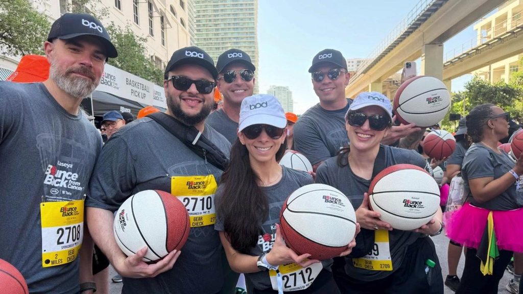 BPD volunteers in team caps holding basketballs at a community youth event