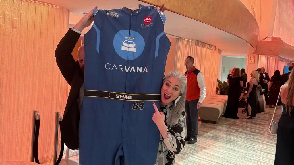 BPD team member holding up a race suit at a charity gala auctio